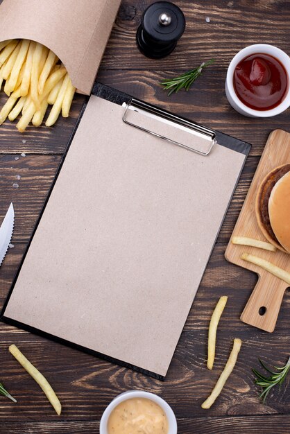 High angle hamburger with fries beside cliboard