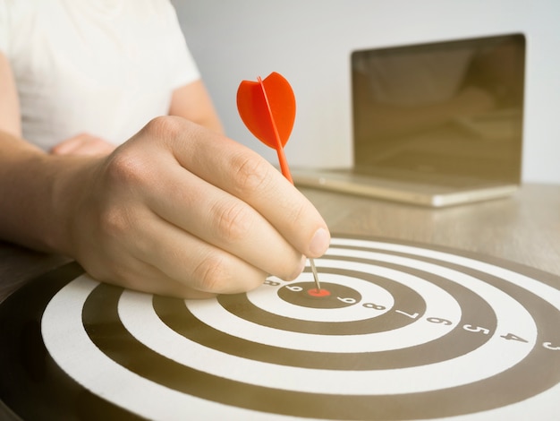 Free photo high angle of hand holding dart on bull's-eye