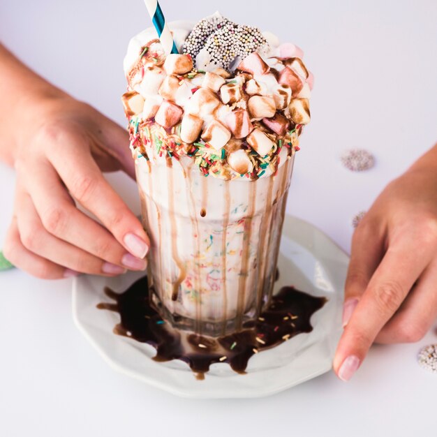 High angle of hand holding milkshake with marshmallow