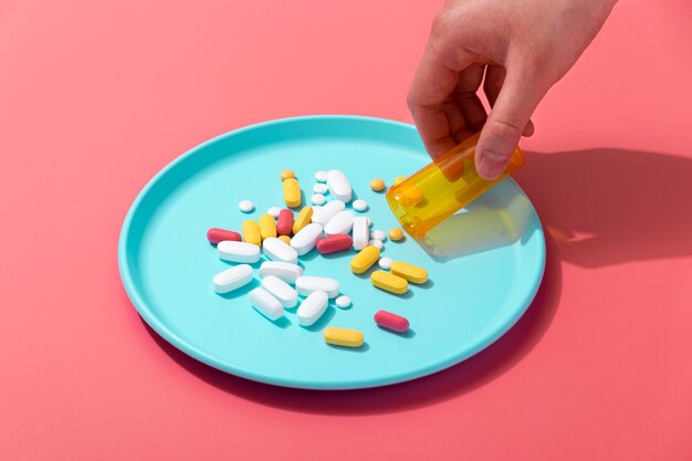 High angle of hand pouring pills on tray out of container