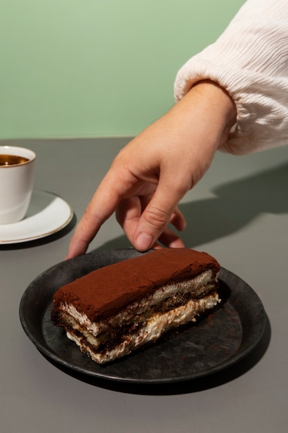 Free photo high angle hand and tiramisu on plate