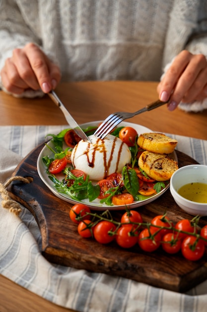 Foto gratuita mani ad alto angolo che tagliano il formaggio