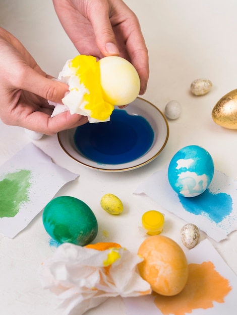 High angle of hands dyeing egg for easter