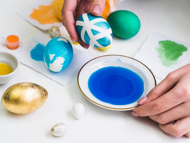 High angle of hands dyeing egg with design for easter