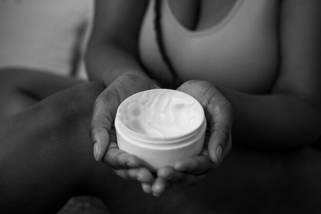 High angle hands holding cream container