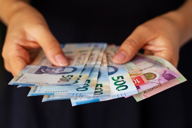 Бесплатное фото Руки под высоким углом держат мексиканские банкноты