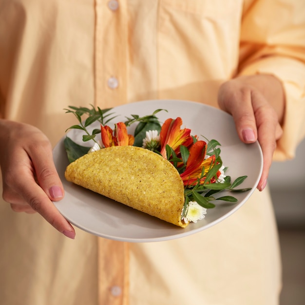 Free photo high angle hands holding plate with taco