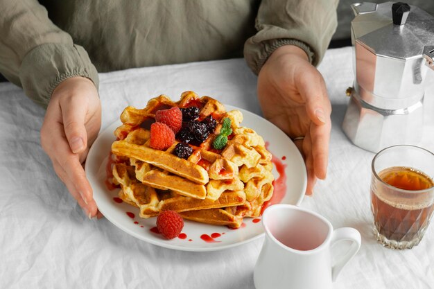 High angle hands holding plate with waffles