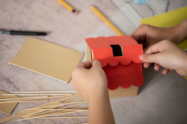 Free photo high angle hands making house's red roof