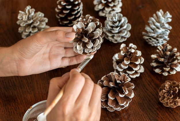 High angle of hands painting pine cones for christmas