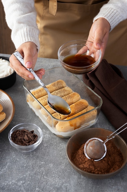 High angle hands pouring coffee over ladyfingers