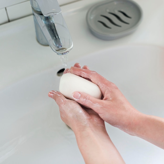 High angle of hands washing with bar of soap and water