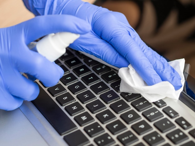 High angle of hands with surgical gloves cleansing keyboard