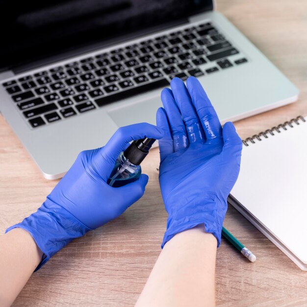 High angle of hands with surgical gloves using hand sanitizer