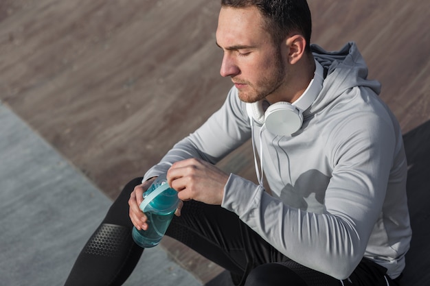 Free photo high angle handsome man holding a bottle of water