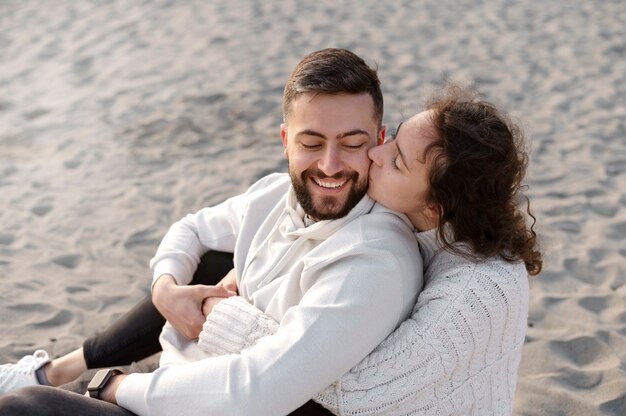 High angle happy couple sitting on beach