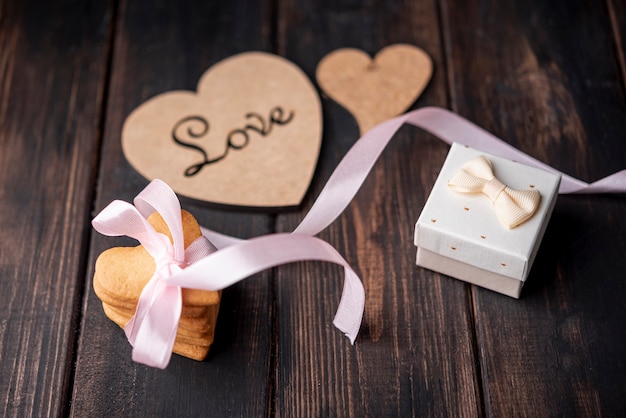 Free photo high angle of heart-shaped cookies with present and ribbon