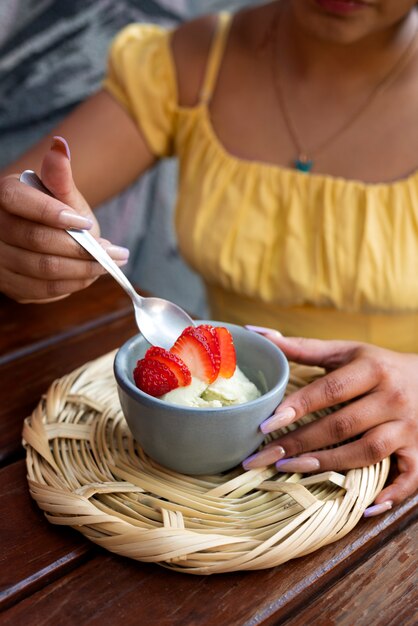 Donna ispanica dell'angolo alto che mangia il gelato all'aperto