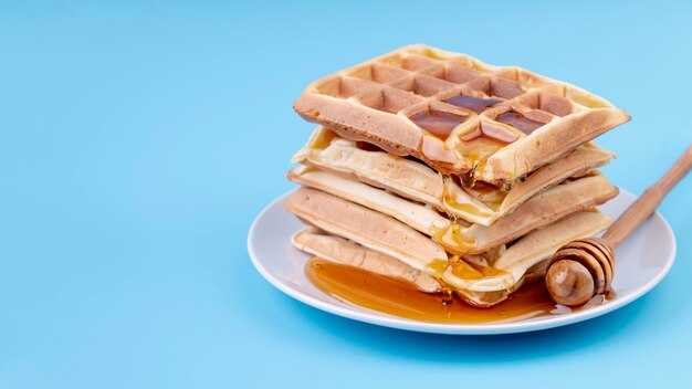 High angle of honey covered stacked waffles on plate with copy space