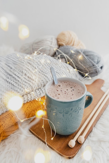 High angle hot chocolate on wooden board with blanket and lights