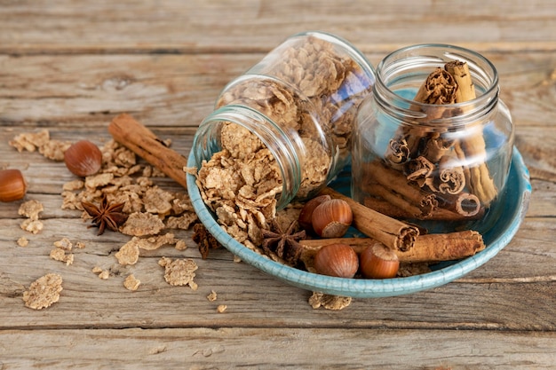 High angle of jars with breakfast cereals and cinnamon sticks