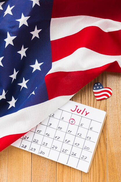 High angle of july month calendar and american flags on wooden surface