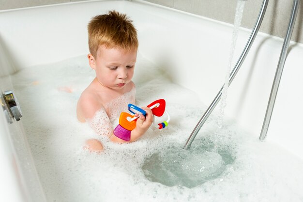 High angle kid in the bathtub with toys