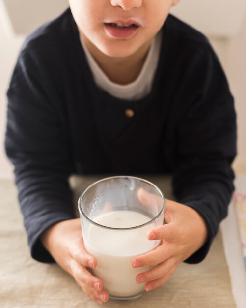 High angle kid holding glass of milk