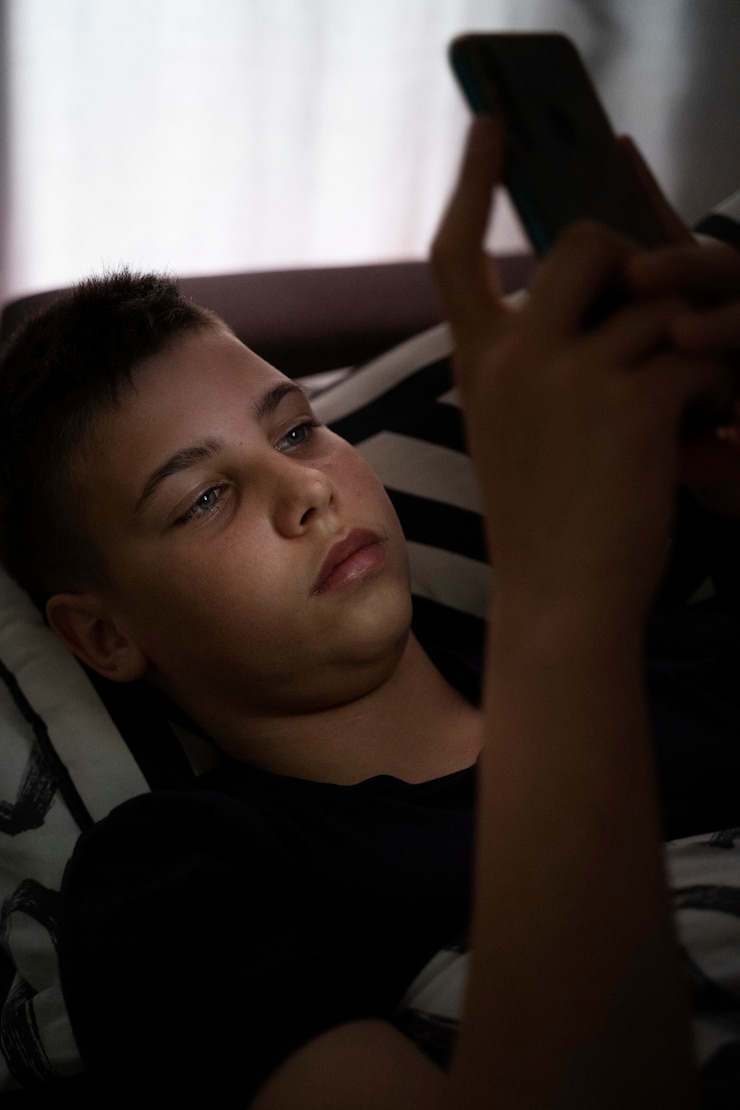 Бесплатный Фотография мальчик с высоким углом, держащий смартфон.
