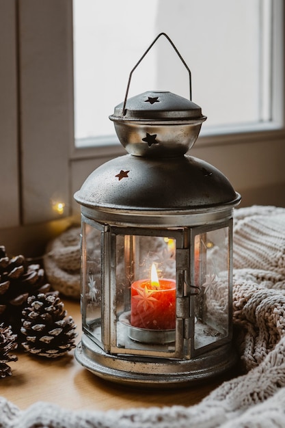 Free photo high angle lamp with candle, pine cones and blanket