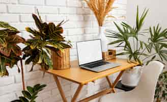 Free photo high angle laptop on table with plants