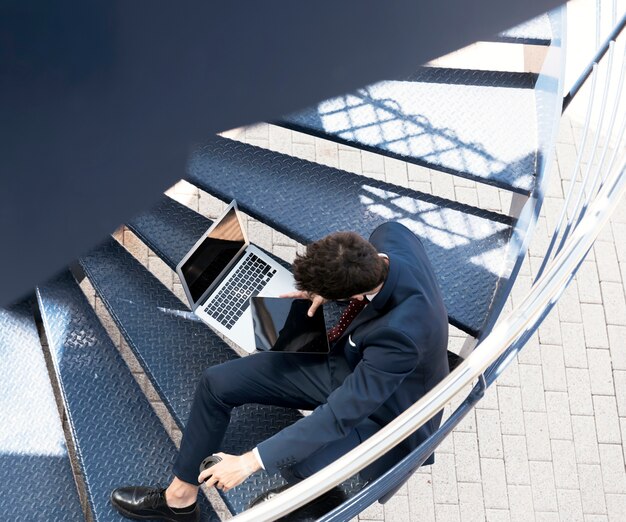 High angle lawyer with laptop and tablet on stairs