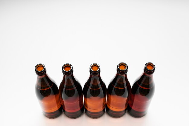 High angle lined up beer bottles on white background with copy space