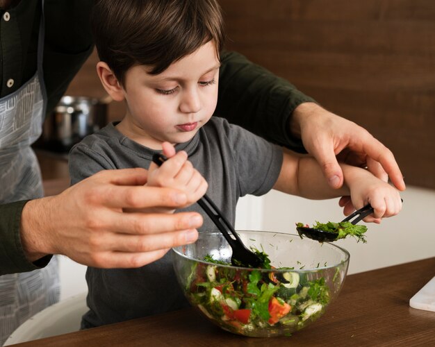 サラダを混合する高角度の小さな男の子