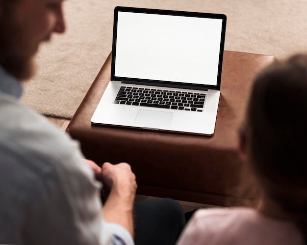 High angle of little girl and dad spending time together next to laptop
