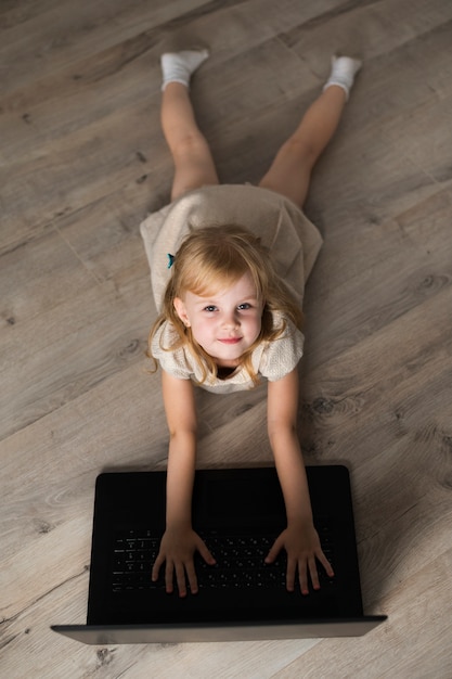 Foto gratuita bambina dell'angolo alto sul pavimento che esamina macchina fotografica