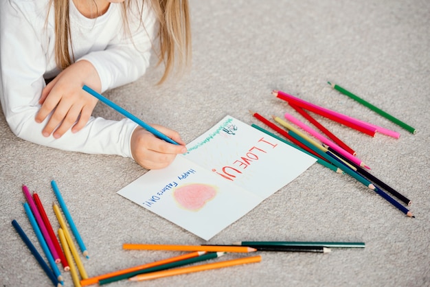 high angle of little girl holding drawing card for father's day