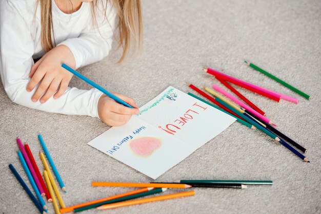 High angle of little girl holding drawing card for father's day