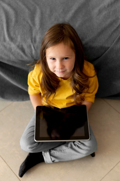 Foto gratuita alto angolo della bambina facendo uso della compressa