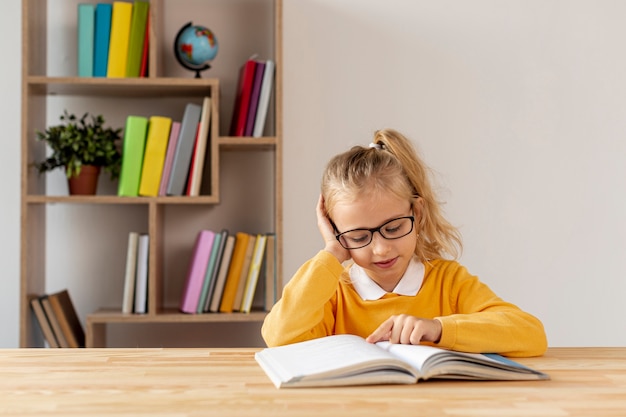 Foto gratuita bambina dell'angolo alto con lettura di vetro