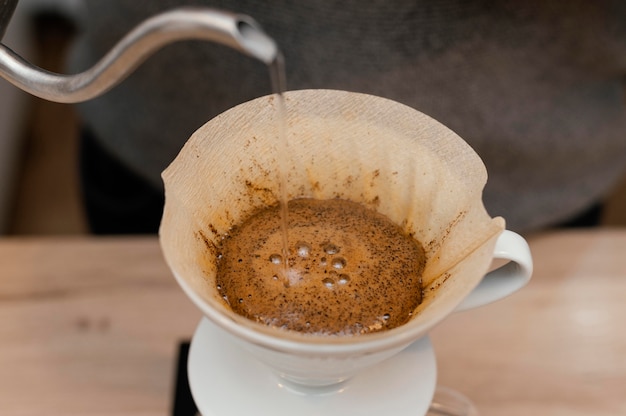 High angle of male barista pouring hot water over coffee filter