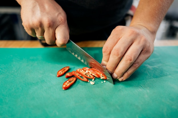 Foto gratuita alto angolo del cuoco unico maschio che taglia il peperoncino rosso