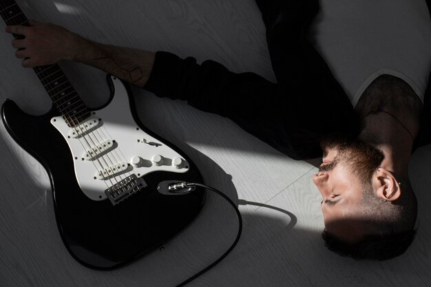 High angle of male performer sitting next to his electric guitar