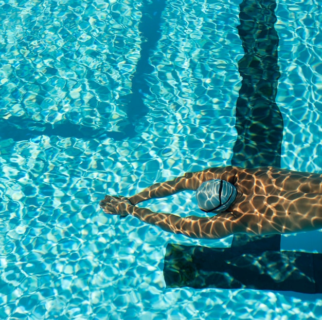 High angle of male swimmer swimming in water pool