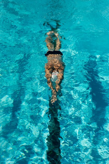 High angle of male swimmer swimming in water pool