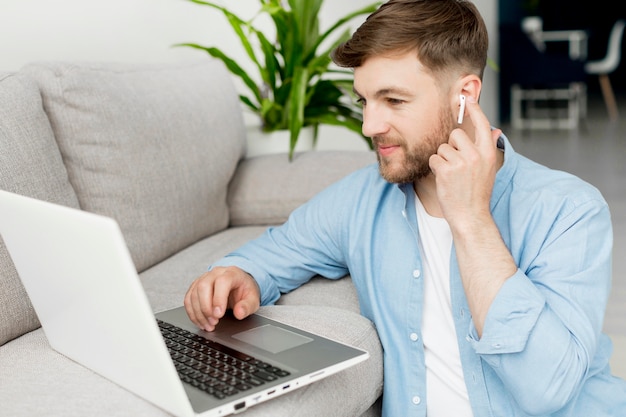 Uomo dell'angolo alto sul pavimento che lavora al computer portatile