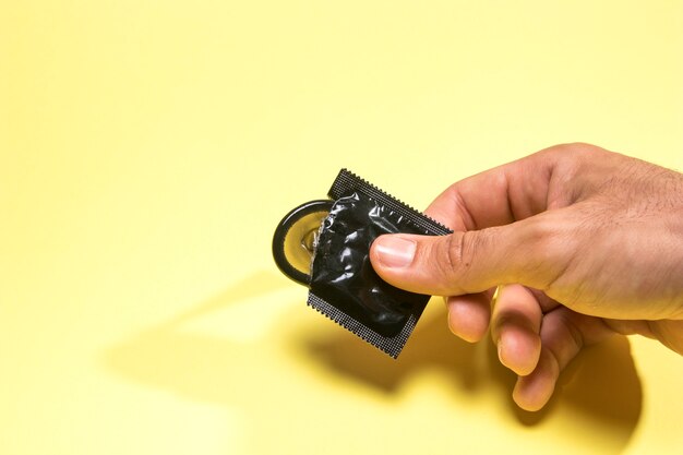 High angle man holding a black condom