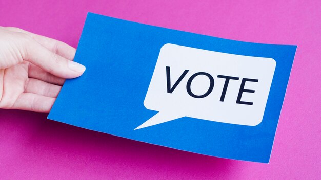 High angle man holding a blue card with vote speech bubble