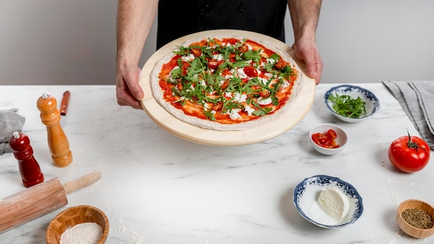 High angle man holding cutting board with pizza