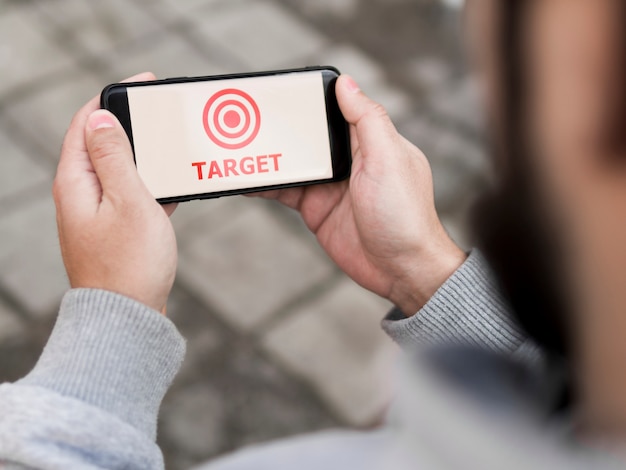 High angle of man holding smartphone with target